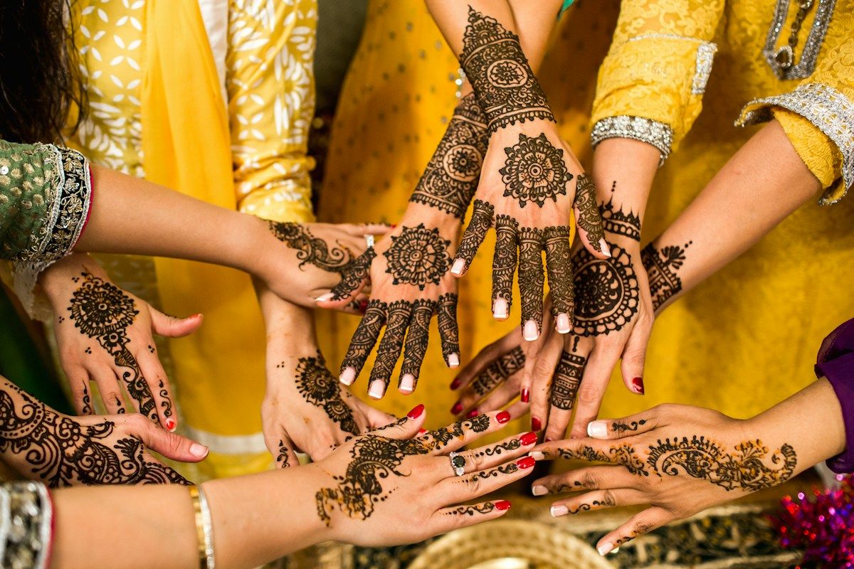 Several women showing hands covered in fresh henna